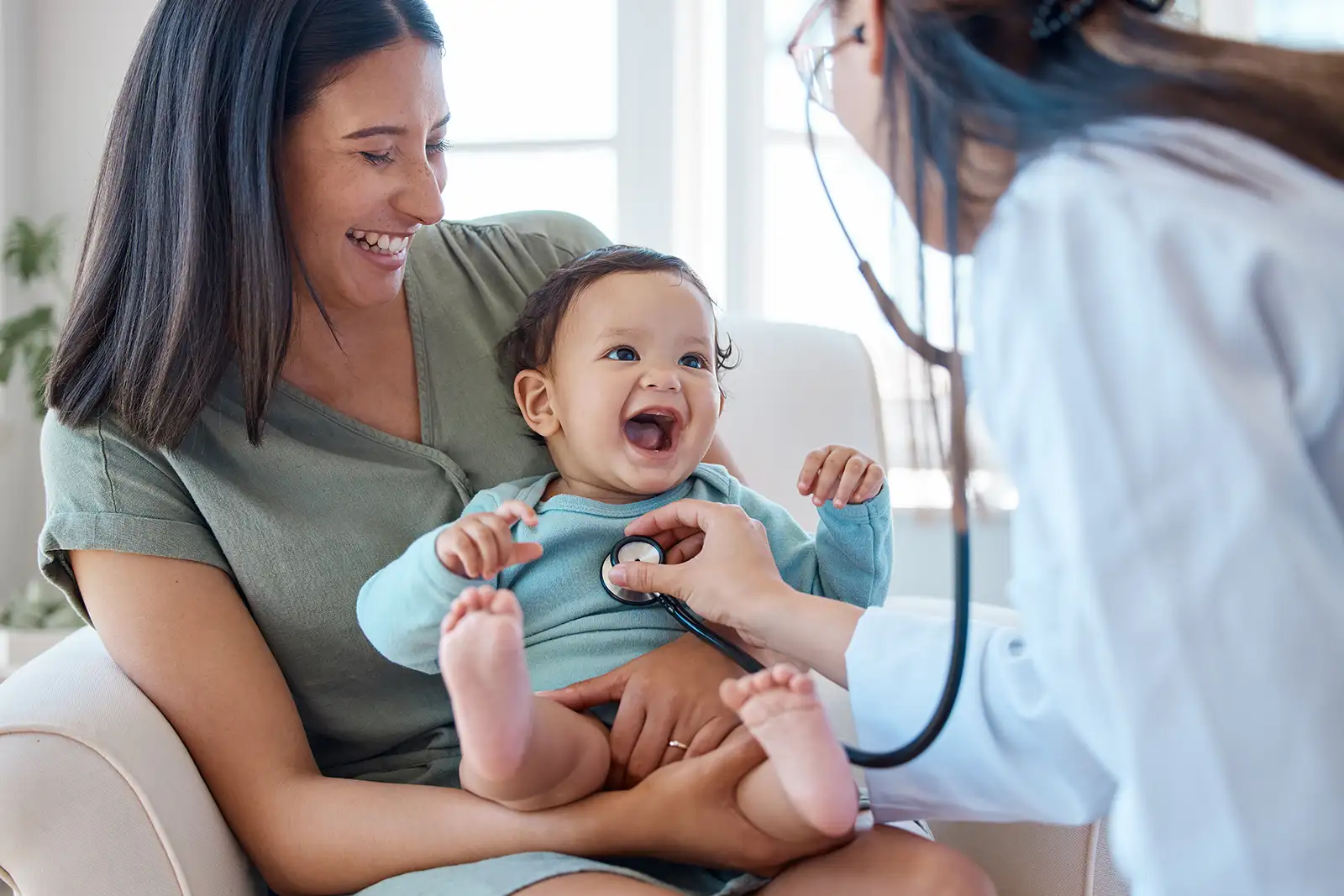 aap-colorado-home-2 A mother holds her smiling baby while a doctor checks its heartbeat.
